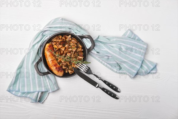 Cast-iron pan with fried sausage and mushrooms