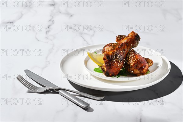 Portion of baked chicken legs with spicy sauce on a plate