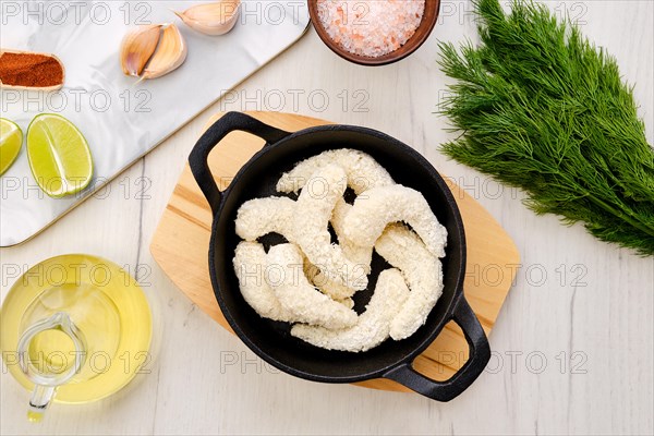 Top view of prepared for frying uncooked shrimps in cheese breading with spice