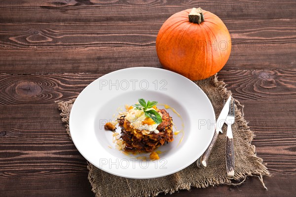 Sweet pumpkin fritters with yogurt with whole pumpkin on background