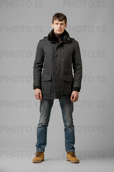 Full length portrait of handsome man in warm winter coat posing in studio