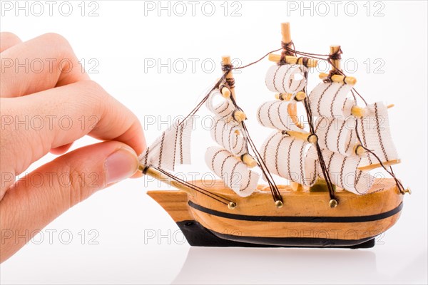 Hand in touch with a little model sailboat on a white background