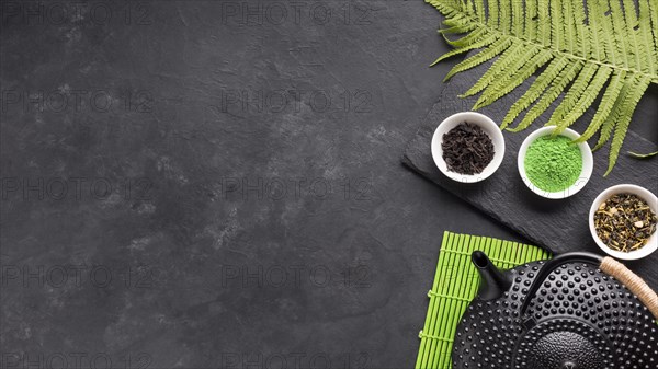 Healthy tea ingredient with black teapot fern leaves backdrop