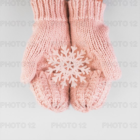 Person hands in mittens with paper snowflake