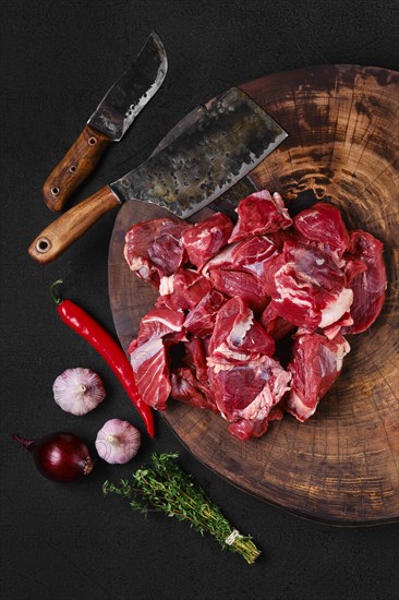 Overhead view of chopping fresh beef meat for goulash or stew on wooden chopping stump