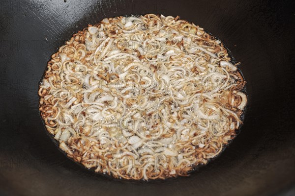 Frying onion in oil in cauldron. The making of pilaf