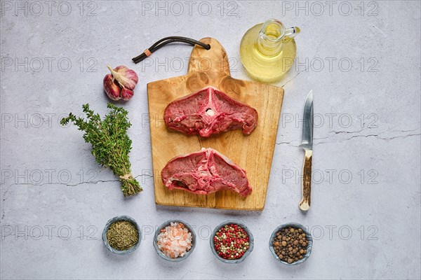 Overhead view of raw fresh deer backstrap with spice and herb over concrete background