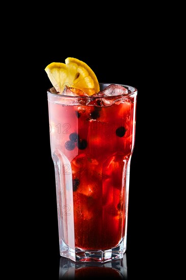 Cold lemonade with orange juice and black currant isolated on black background