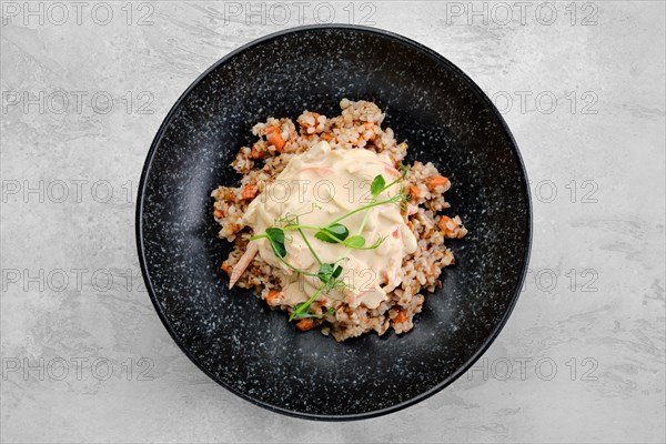 Buckwheat porridge with slices of fried carrot and creamy flour sauce on a plate