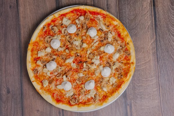 Top view of pizza with mushrooms and mayonnaise sause cutted on pieces