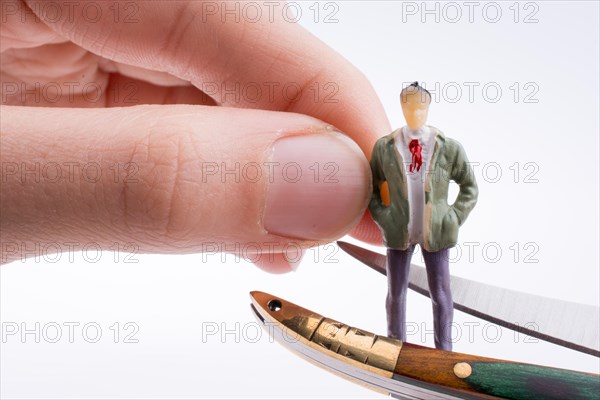 Hand holding a pocket knife near a human figure on a white background