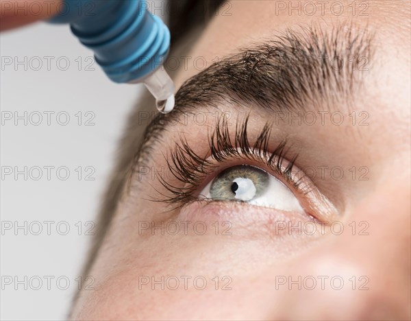 Handsome man using eye drops close up