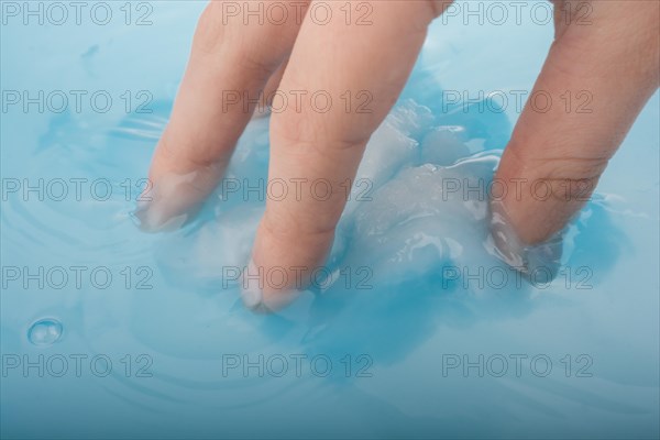 Hand holding some cotton in blue water