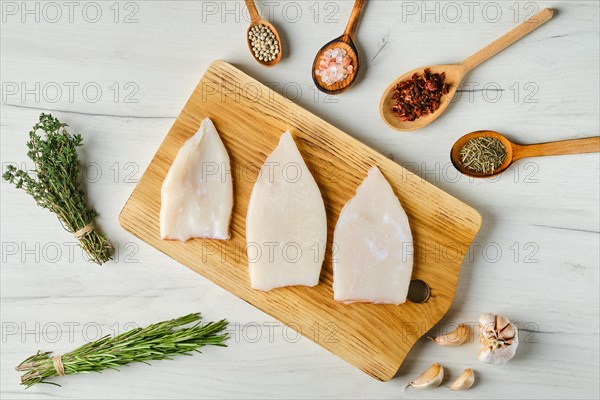 Overhead view of raw frozen squid fillet on wooden cutting board