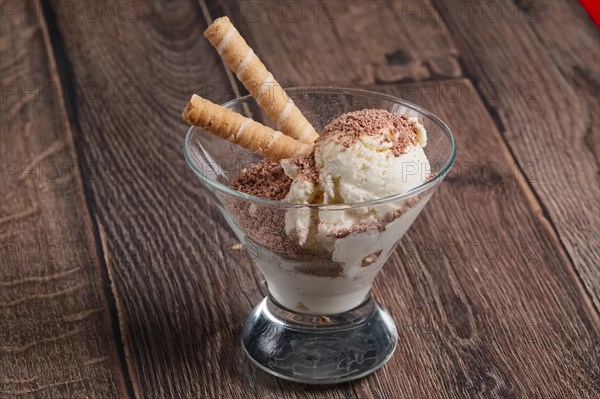 Ice cream with chocolate and cookie in glass on wooden table