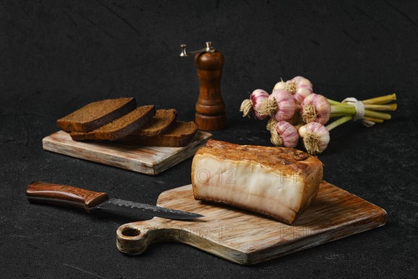 Smoked fat with brown bread on wooden cutting board