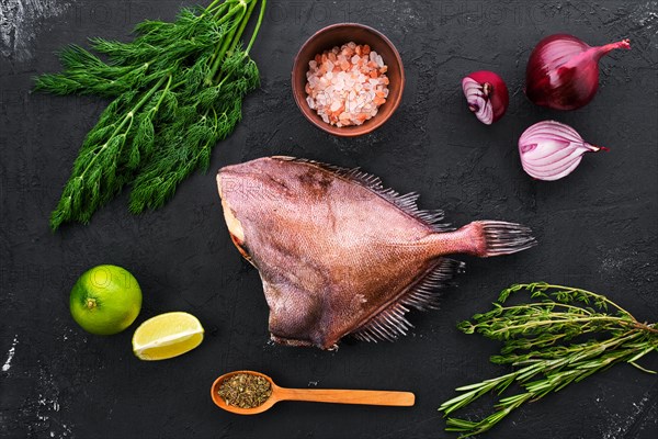 Raw crimson sea bream with spice and herbs on black concrete background