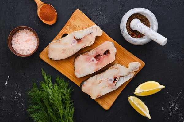 Top view of fresh raw cod steak on wooden cutting board with spice