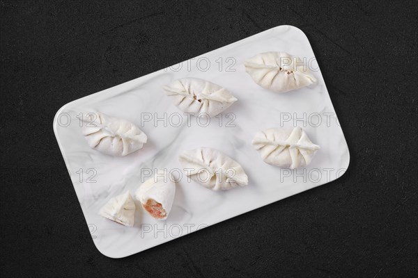 Top view of frozen dumplings stuffed with liver and provencal herbs on marble serving plate