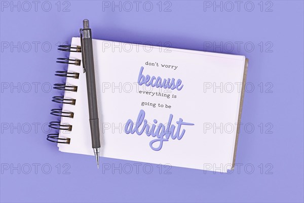 Text 'Don't worry because everything will be alright' in notebook on violet background