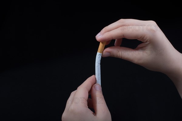 Hand is breaking a cigarette on a black background