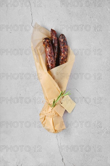Overhead view of dried sausage made of venison spicy meat and lard in wrapping paper