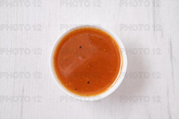 Overhead view of small bowl with spicy orange sauce for poultry