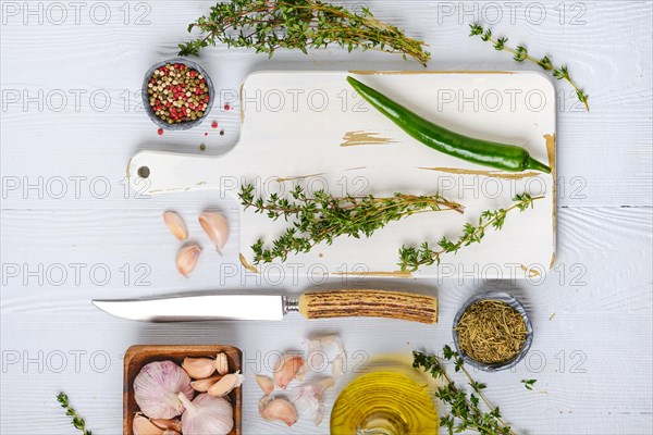 Overhead view of wooden cutting board with fresh thyme and spices for piquant sauce or marinade on wooden kitchen table