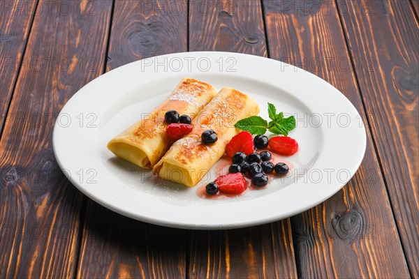 Plate with thin pancakes stuffed with curd and served with berry jam