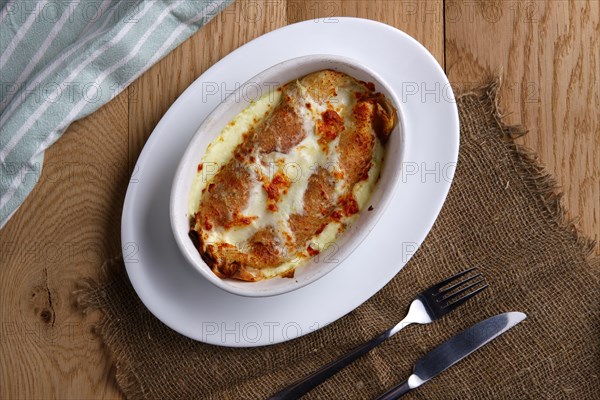 Top view of fried pancakes stuffed with ham and covered with melted cheese on wooden table