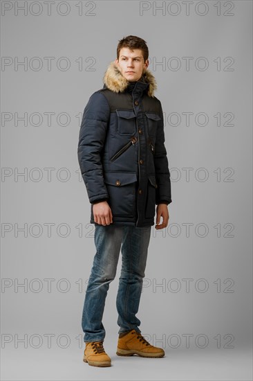 Full length portrait of handsome man in warm winter coat posing in studio