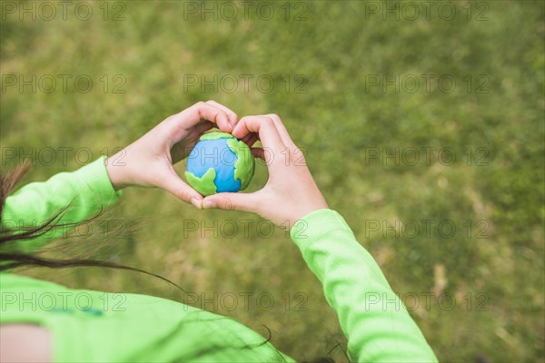 Heart shape hands surrounds colorful plasticine planet
