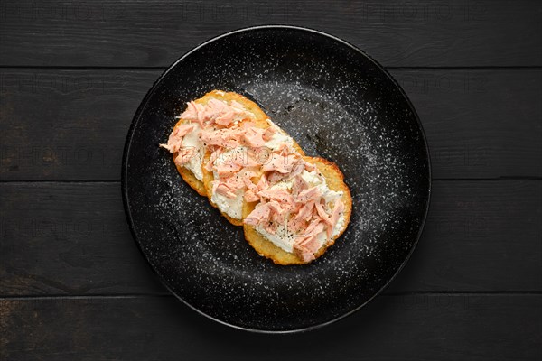 Top view of fried potato patties with greek yogurt and salmon on a plate