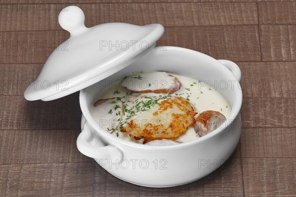 White bowl with machanka and potato pancakes on wooden table