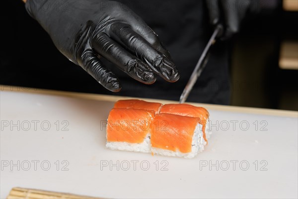 Chef cuts salmon rolls with knife