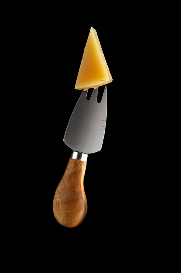 Cheese fork with piece of parmesan on it isolated on black background