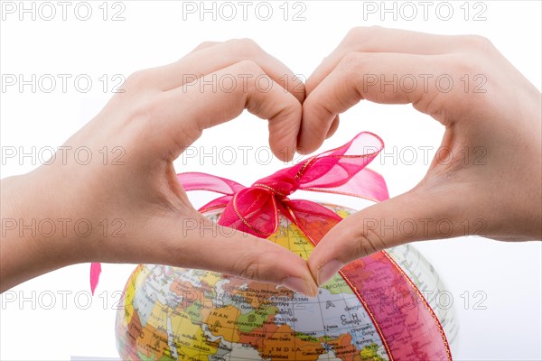 Little model globe behinf a heart shaped hand