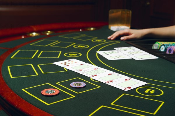 Casino black jack table with chips and cards. Winning combination. Hand of Croupier behind gambling table