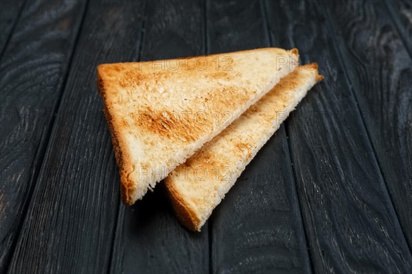 Two pieces of toast bread on dark wooden table. Top view