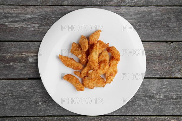 Crisp grilled chicken wings on a white dish on wooden table