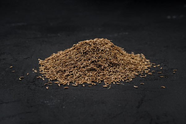 Pile of caraway scattered on dark background