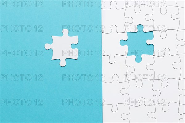 Single white jigsaw puzzle piece blue background