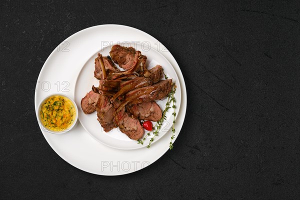 Overhead view of grilled rack of lamb on a plate with spicy sauce