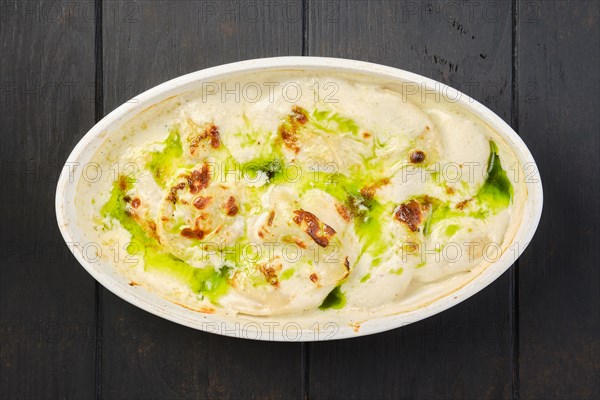 Overhead view of pork dumplings with mushroom and onion sauce baked in oven