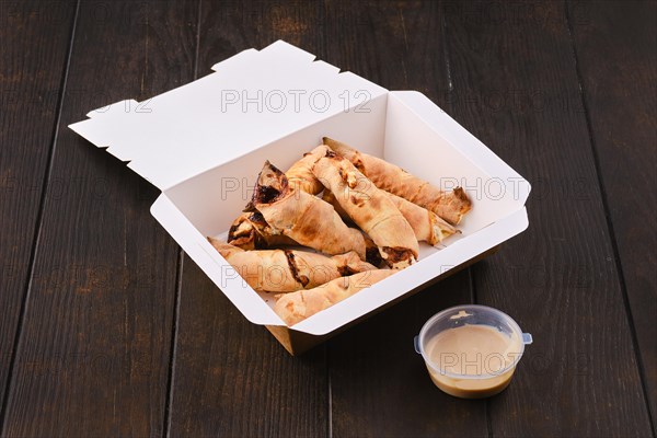 Slices of pear rolled in dough with caramel sauce in take away cardboard box