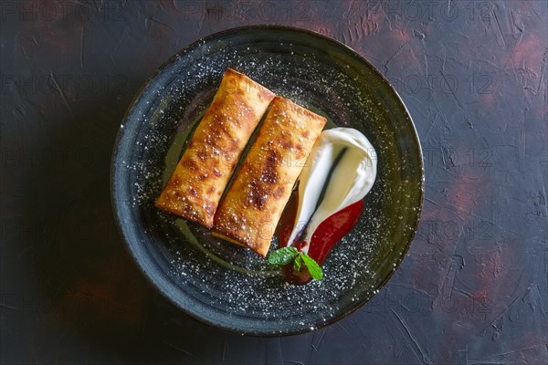 Sweet pancakes stuffed with curd and decorated with sour cream and strawberry jam