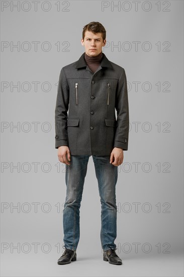 Full length portrait of handsome man in warm woolen coat posing in studio