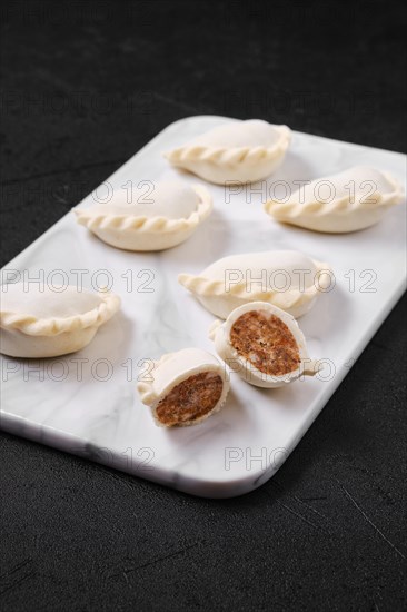 Frozen dumplings stuffed with beef meat and provencal herbs on marble serving plate