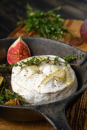 Closeup view of baked in oven camembert cheese and figs ready for baking on frying pan