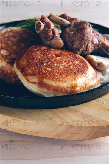 Fried in oven rabbit with fritters and onion sauce. Cast iron pan on wooden cutting board